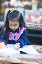 A little girl coloring in a coloring book 