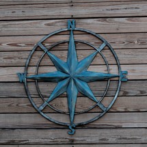 metal sculpture compass rose against wood boards 