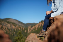 a woman sitting on a rock praying 