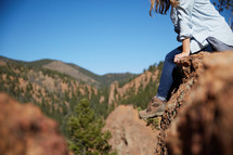 a woman sitting on a red rock resting 