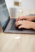 a woman typing on a laptop at a desk 