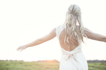 bride standing outdoors with open arms 