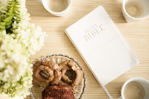 Bible and a plate of donuts on a table.