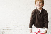 a young boy holding a wrapped Christmas gift 