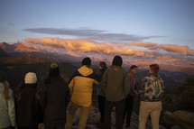 group of friends watching the sunrise on a mountaintop 