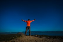 a man with outstretched arms standing on a mountaintop 