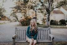 woman sitting on a wooden bench smiling 