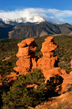 clouds over snow capped mountain peaks and red rock formations 