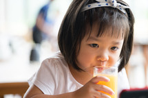 a little girl drinking orange juice 