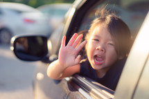 a child waving out of a car window 