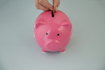 placing a coin in a piggy bank 