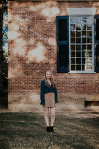a young woman standing in front of a brick building 