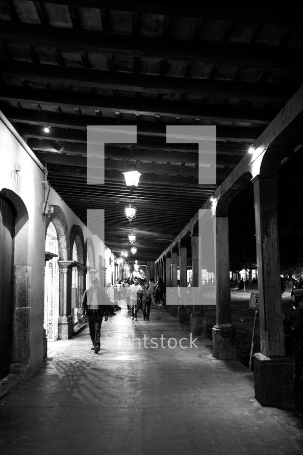 people walking under a covered walkway at night 