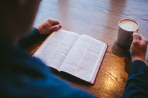 man reading an open Bible on a table 
