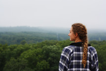 a young woman looking out into a forest 