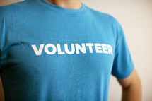 A man wearing a blue t-shirt with the word "volunteer" printed on it.