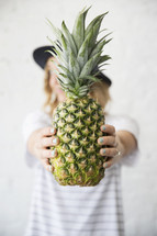 a woman holding a pineapple 