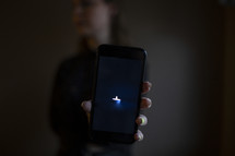 young woman holding image of tiny candle on smart phone