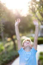 Little boy raising hands to the sky 