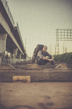 man sitting on the ground outdoors with a backpack 