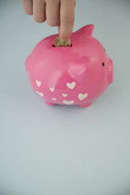 placing a coin in a piggy bank 