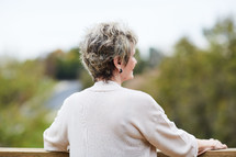 a woman standing looking over a railing thinking 