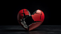 Broken red heart on a black background. 