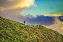 man kneeling in prayer on a green mountaintop 