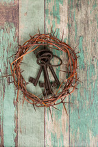 crown of thorns and skeleton keys on a green wood background 