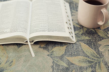 open Bible on floral fabric and coffee cup 