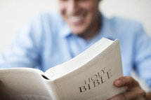 Smiling man reading the Bible.