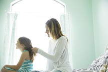 a mother braiding her daughter's hair 