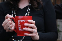 a woman holding a winter coffee mug 