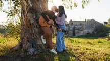 Couple playing music with guitar under the tree for valentines day