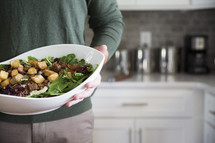 a man holding a large salad bowl 