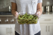 a woman holding green beans 