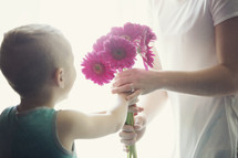a boy giving his mother flowers for mother's day 