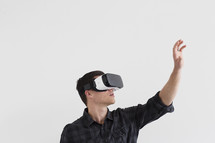 A man reaches into the air while wearing a virtual reality headset.