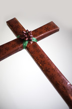 Red wrapped present  shaped like a cross with red and green bow in cenrer.