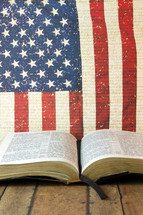 An open Bible in front of an American flag.