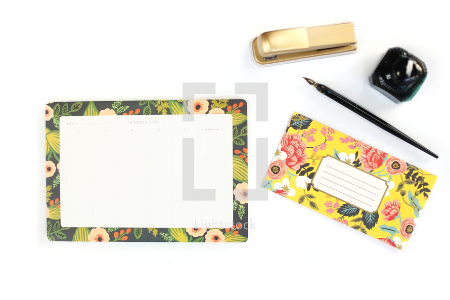 floral stationary set, stapler, and ink pen on a desk 