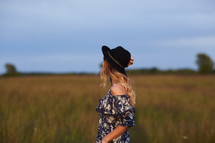 a woman in a dress walking through a field 