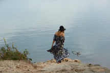 woman in a dress standing on a shore  