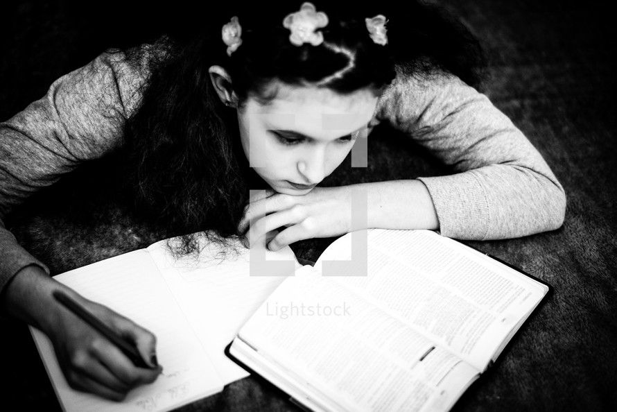 teen girl reading a Bible on a bed 