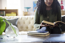 An African American woman reading a Bible in a living room 