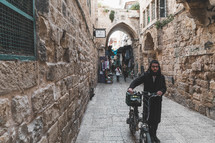 man walking with a bicycle through the streets of old city Jerusalem 
