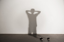 shadow of a man with his hands behind his head and shoes 