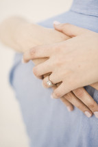 engagement ring on a woman's hand hugging her fiancé 
