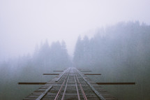 train tracks on a bridge and fog