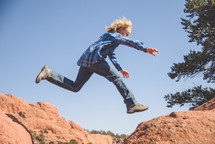 boy child leaping across rocks 